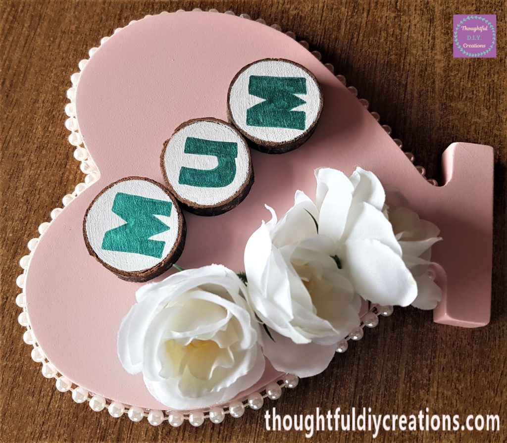 The 3 wood slices hot glued to the heart under one another at an angle.