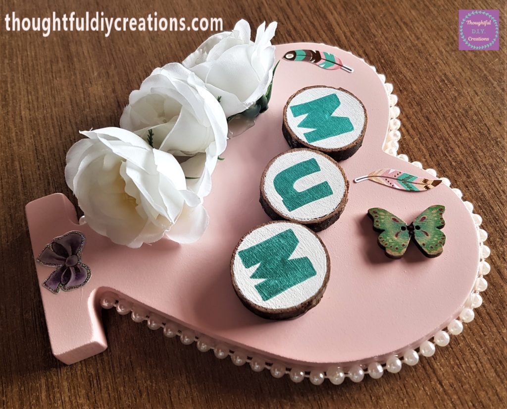 Another feather sticker added to the heart. A wooden butterfly hot glued to the heart.