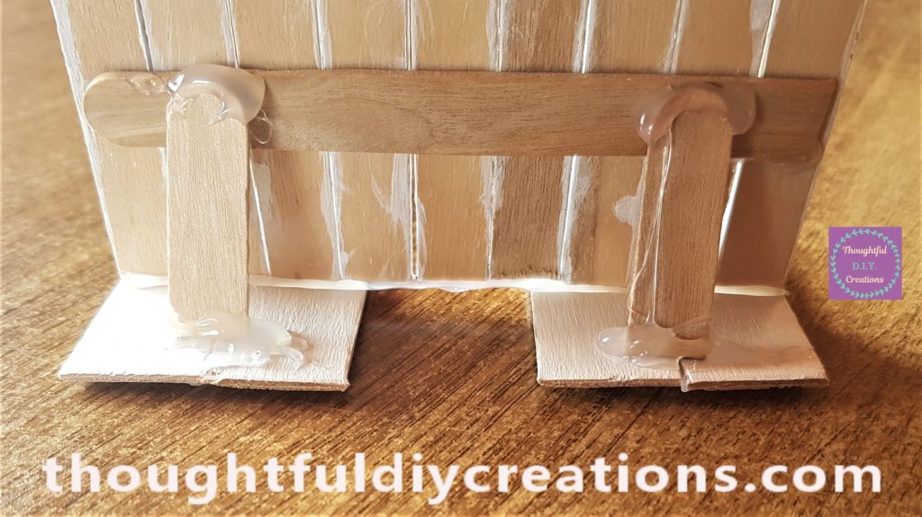 The Bunny's feet cut the same length at the back. 2 cut lollipop sticks hot glued to the back of the door.