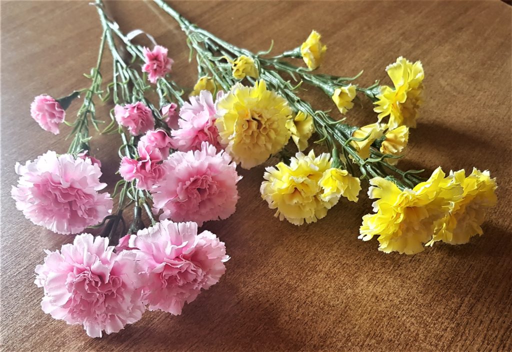 Bunch of faux pink flowers and a bunch of faux yellow flowers.