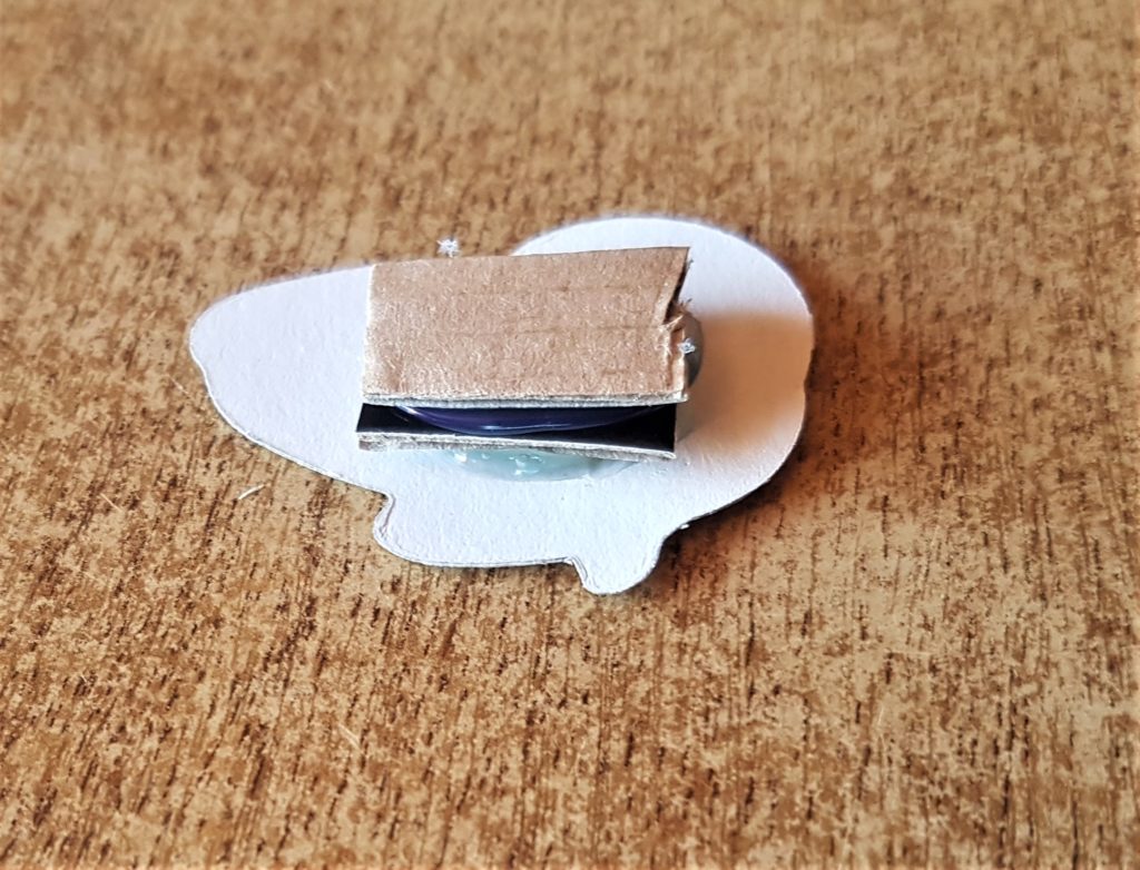 A few squares of cardboard hot glued to the back of the butterfly for extra height.