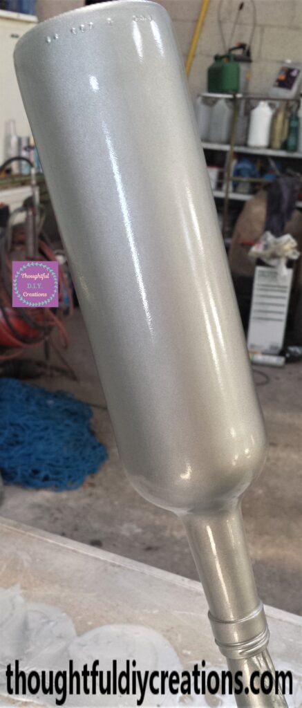 The third and final layer of spray paint applied to the wine bottle.