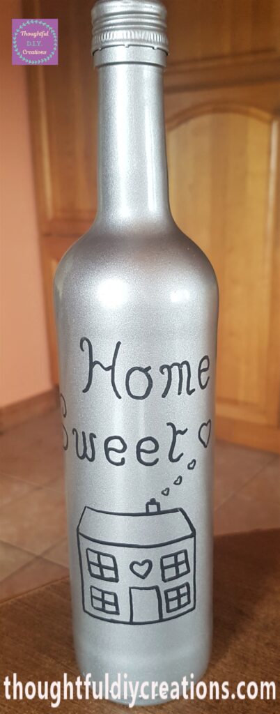 A House drawn on the bottle with 3 small love hearts coming out of the Chimney and a bigger love heart beside the word 'Sweet'.