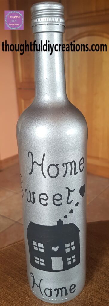 The word 'Home' written on the bottom of the up-cycled wine bottle.
