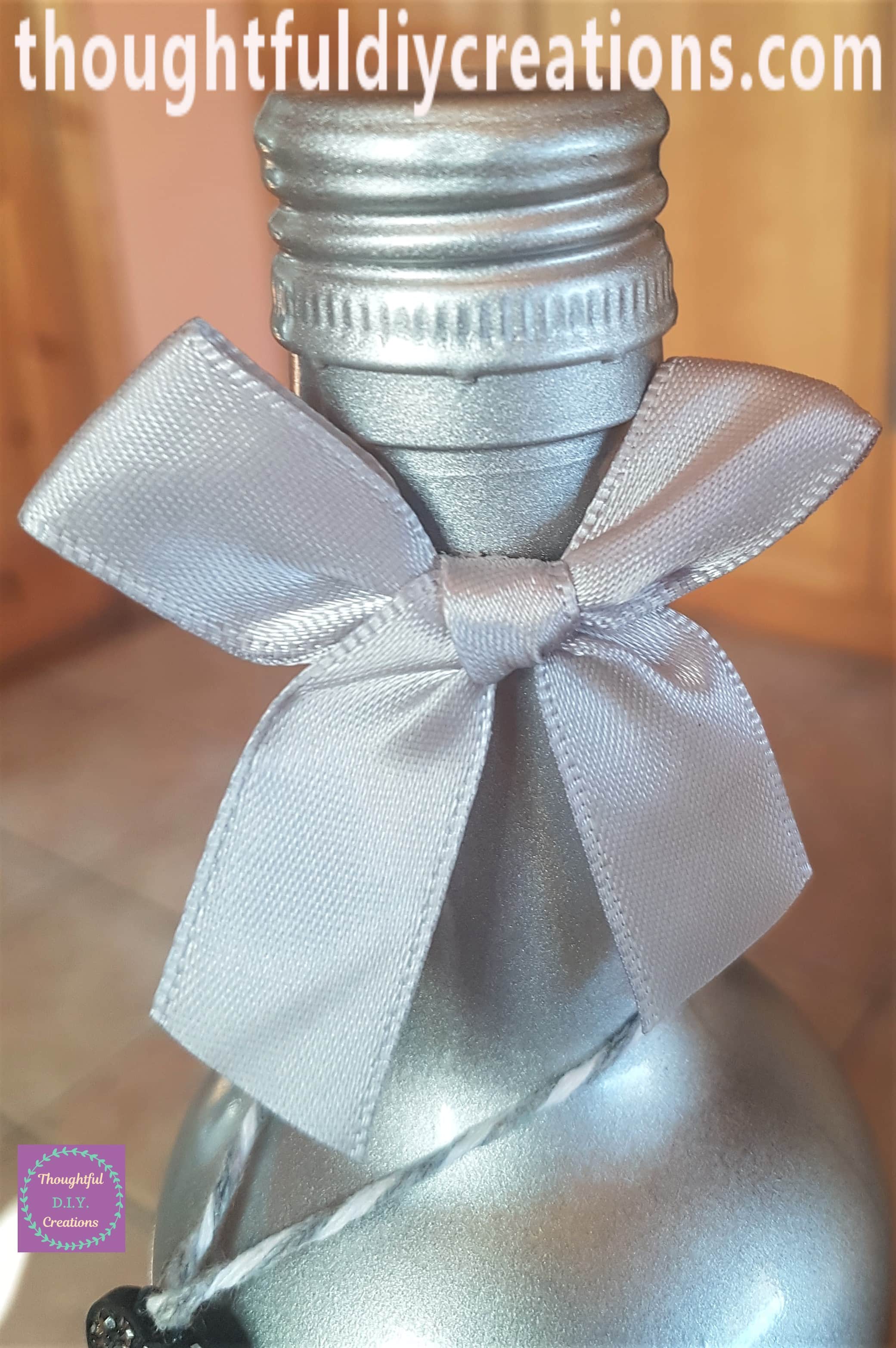 Silver bow attached to the top of the up-cycled wine bottle with a Glue Dot.