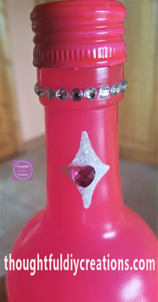 The gemstones removed from the backing and attached to the top of the bottle.