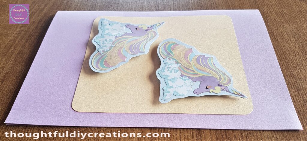 The 2 Unicorn Pictures attached to the Peach Card using a Hot Glue Gun.