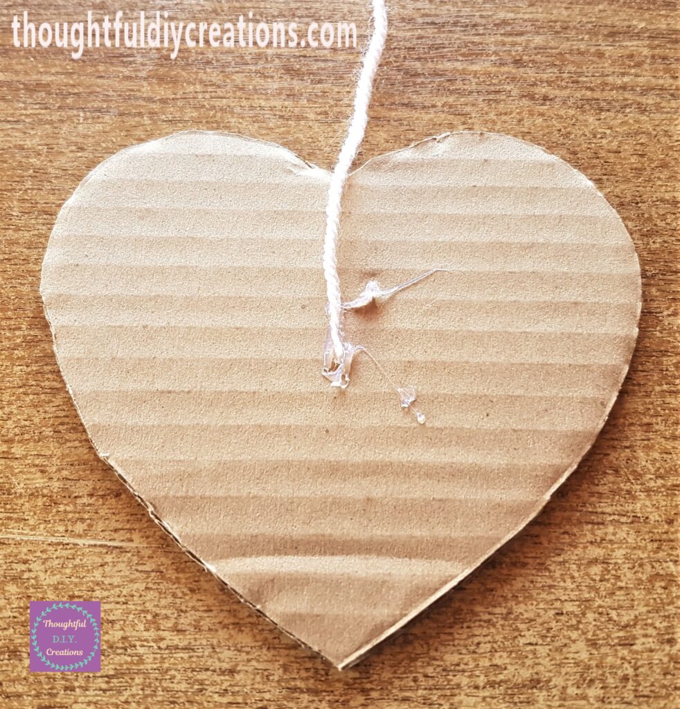 A dab of Hot Glue on the mid-section of the heart, the end of the wool attached to the glue.