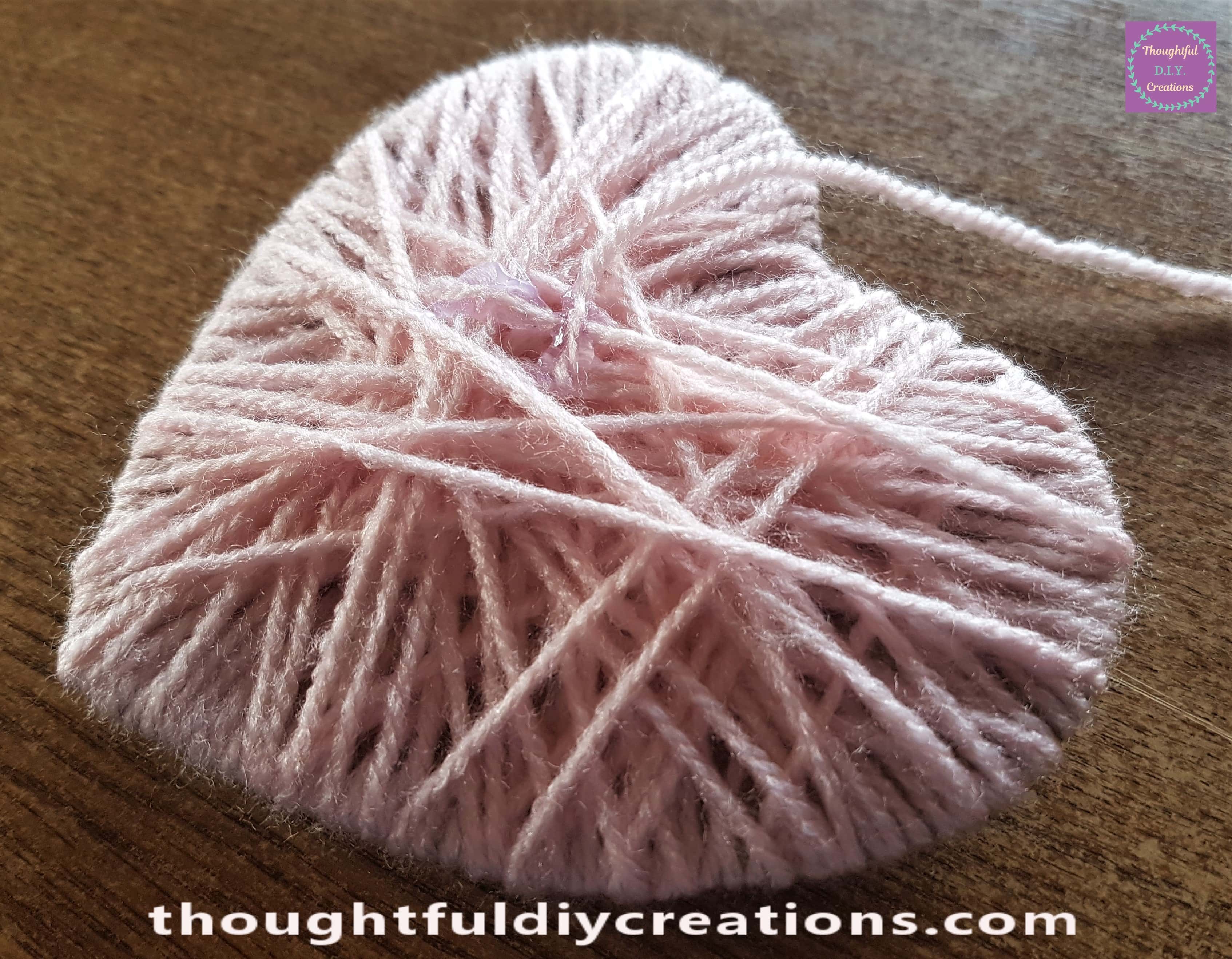 Dab of hot glue on the back of the heart and attached more wool to it.