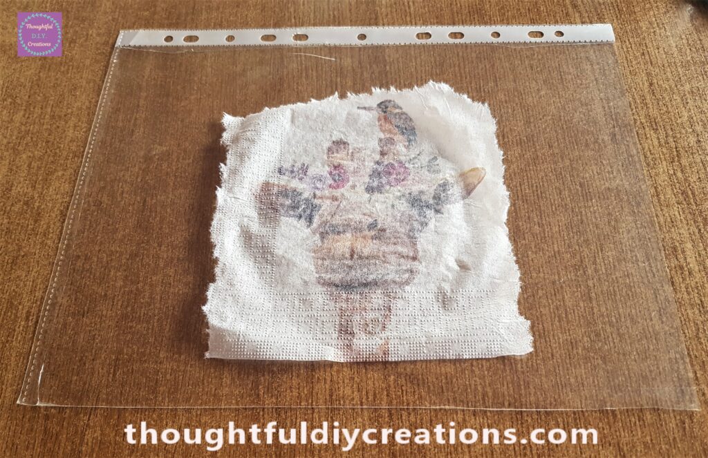 I Cut the opening from the Punched Plastic Sheet leaving 1 flat plastic sheet, the decoupage napkin face down on the plastic sheet.