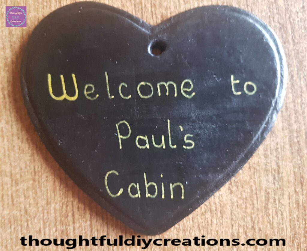 Gold uni POSCA Acrylic Paint Pen and wrote 'Welcome to Paul's Cabin' on the Clay Heart using the Pen.