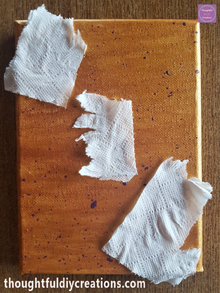 I tore some tissue and covered up the stars on the canvas. I added water to the purple paint and added splatters randomly on the canvas.