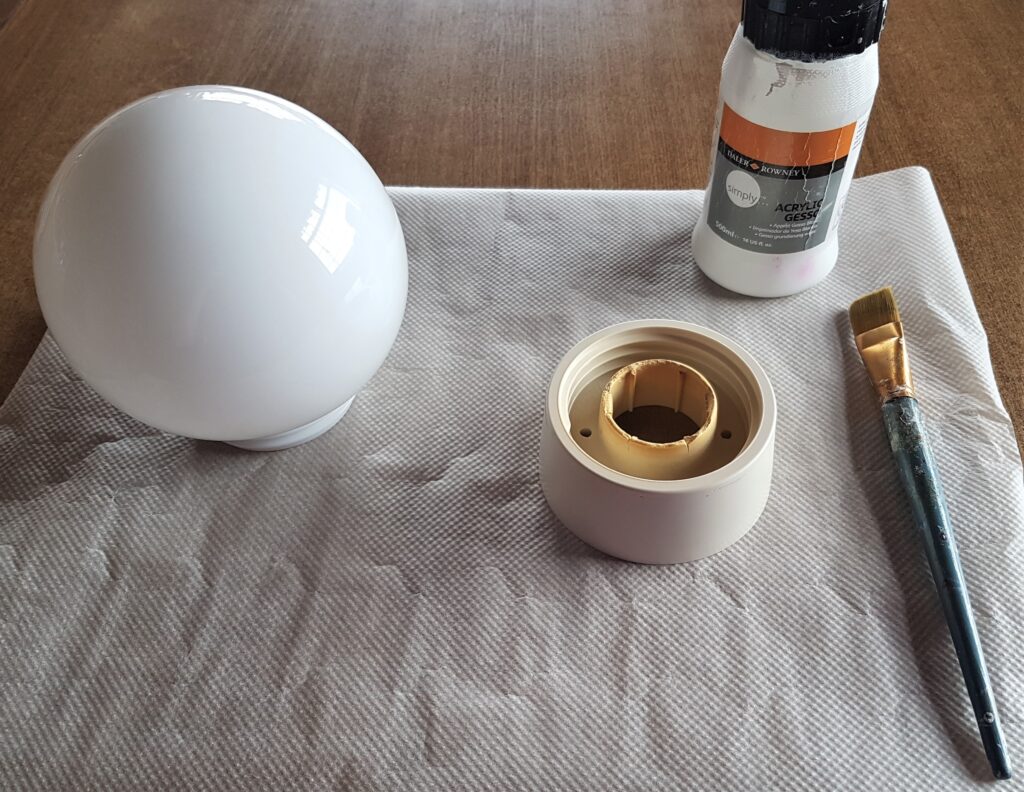 Baking Paper on the Table. Acrylic White Gesso and a Paintbrush ready to prime the Bulb and Stand.