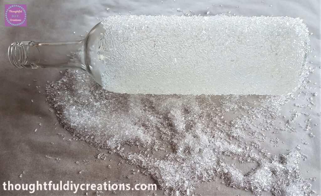 I rolled the bottle over to the back to attach the epsom salts to the mod podge. I sprinkled some epsom salts on any gaps on the bottle.