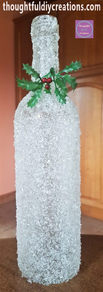Full view of the frosted glass bottle with holly attached.