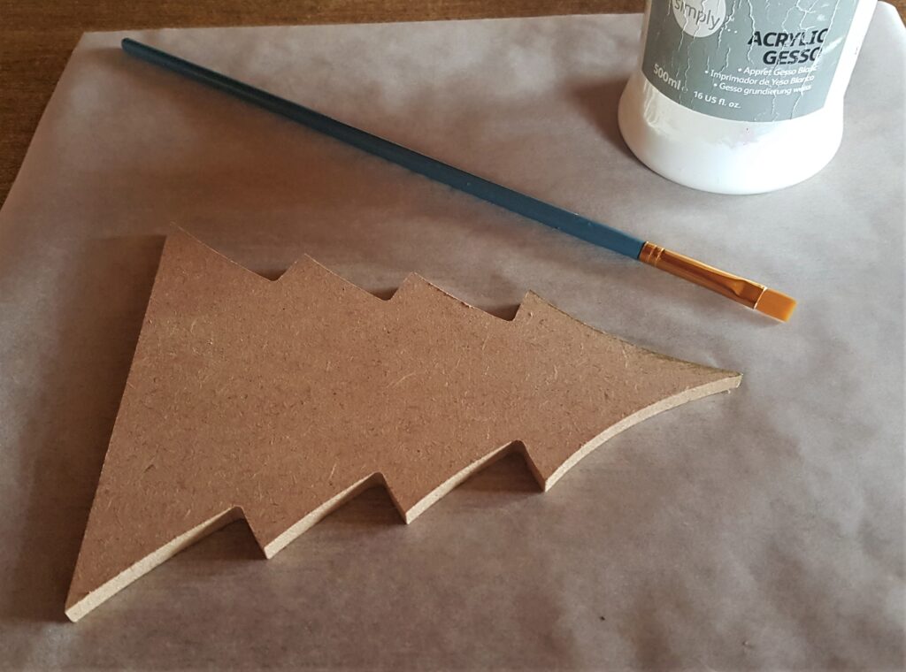 A sheet of baking paper on the table. Acrylic white gesso and a small flat paintbrush.