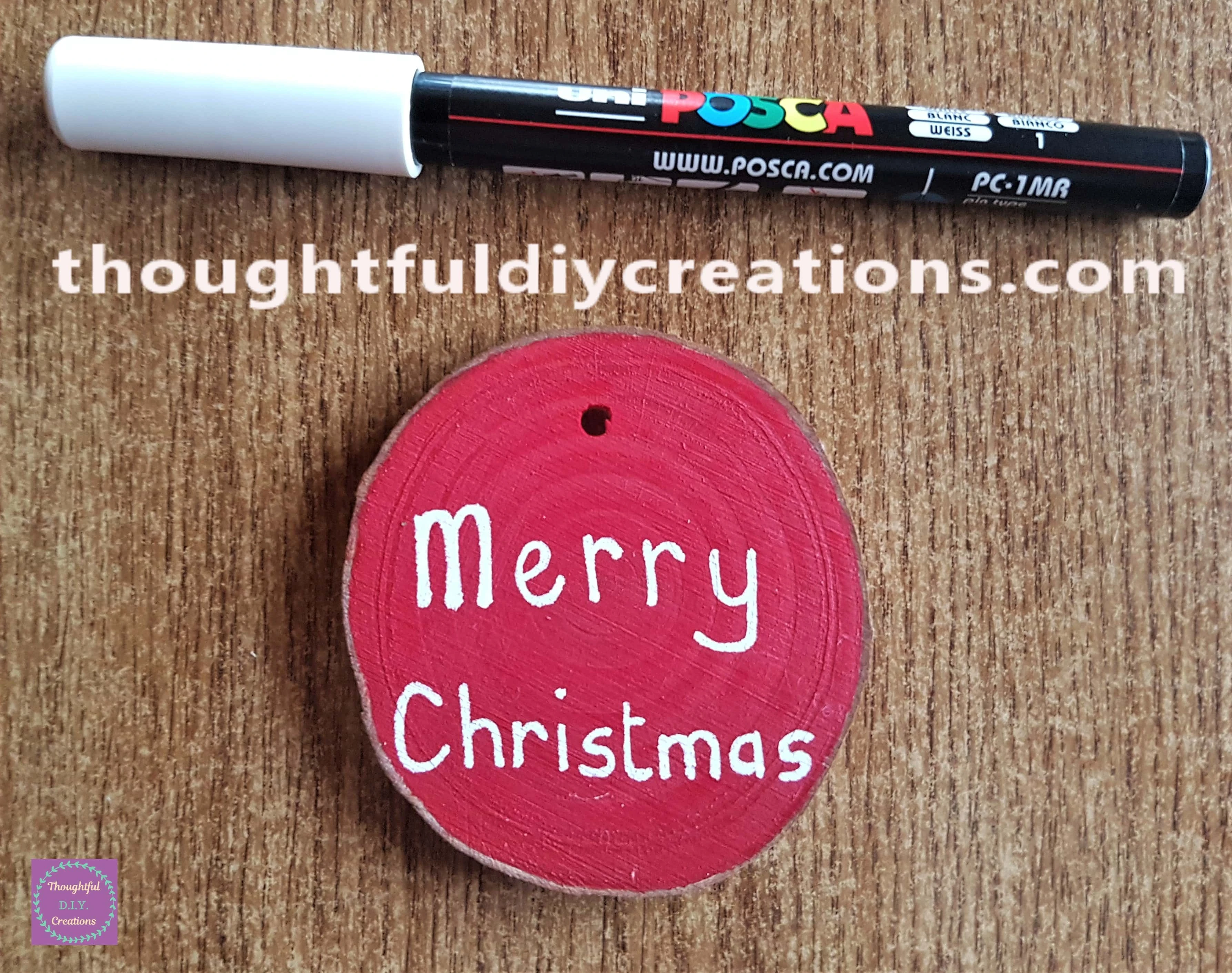 Merry Christmas wrote on the Red Wood Slice with a White uni POSCA Acrylic Paint Pen 0.7 mm.