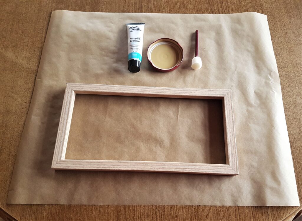 Frame on a Sheet of Baking Parchment Paper. Flat sponge with handle, white acrylic paint and a Lid to hold the Paint.
