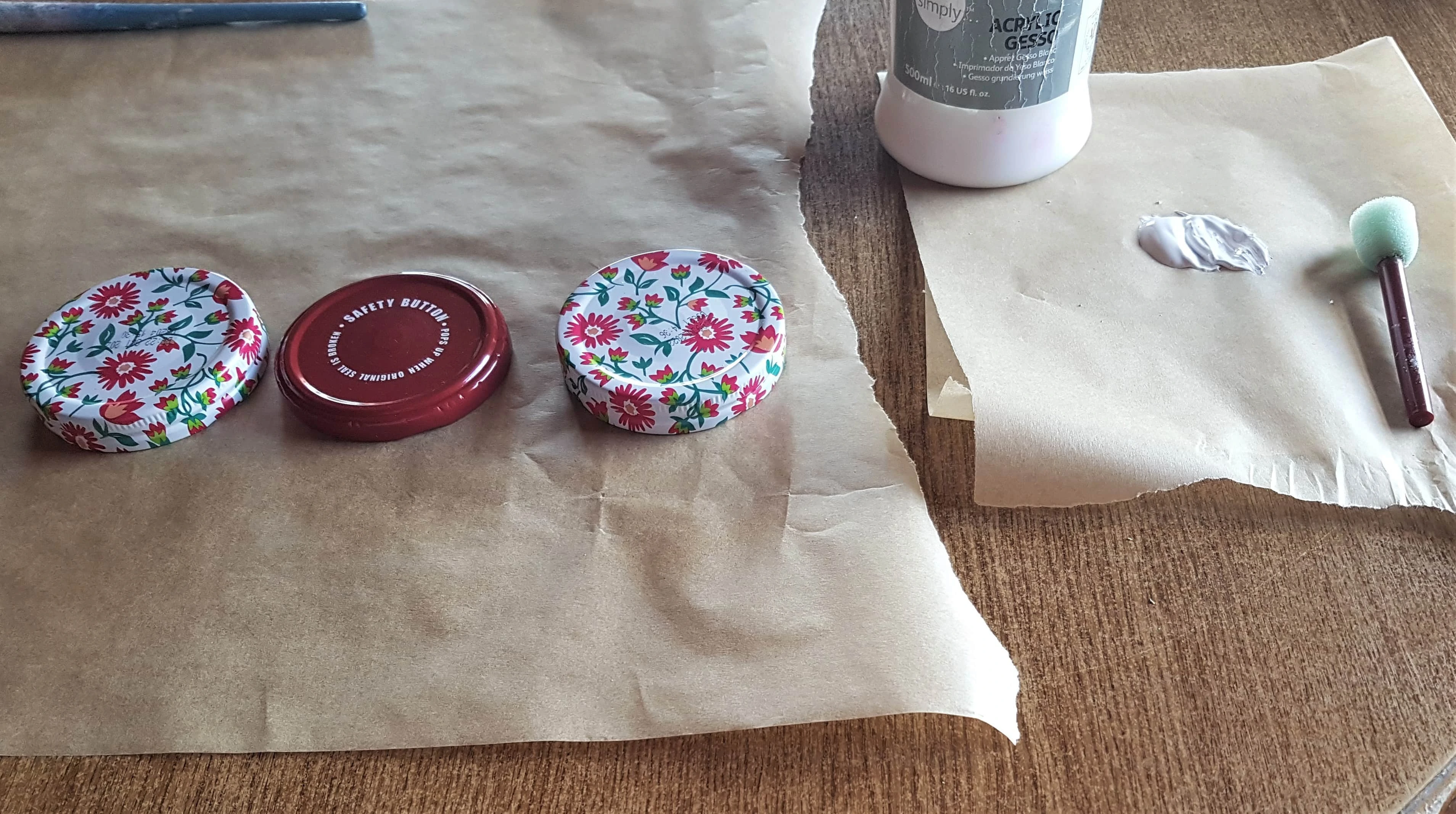 Sheet of Baking Paper on the Table to protect it. 3 lids on the Baking Sheet. Gesso, Sponge on another piece of Baking Paper.