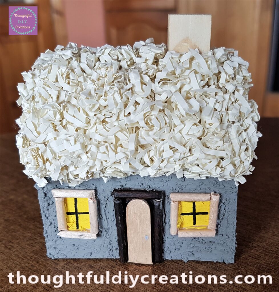 I attached the Raffia to the Roof, and the Chimney next. I cut the end of a lollipop stick and Hot Glued it over the Door.