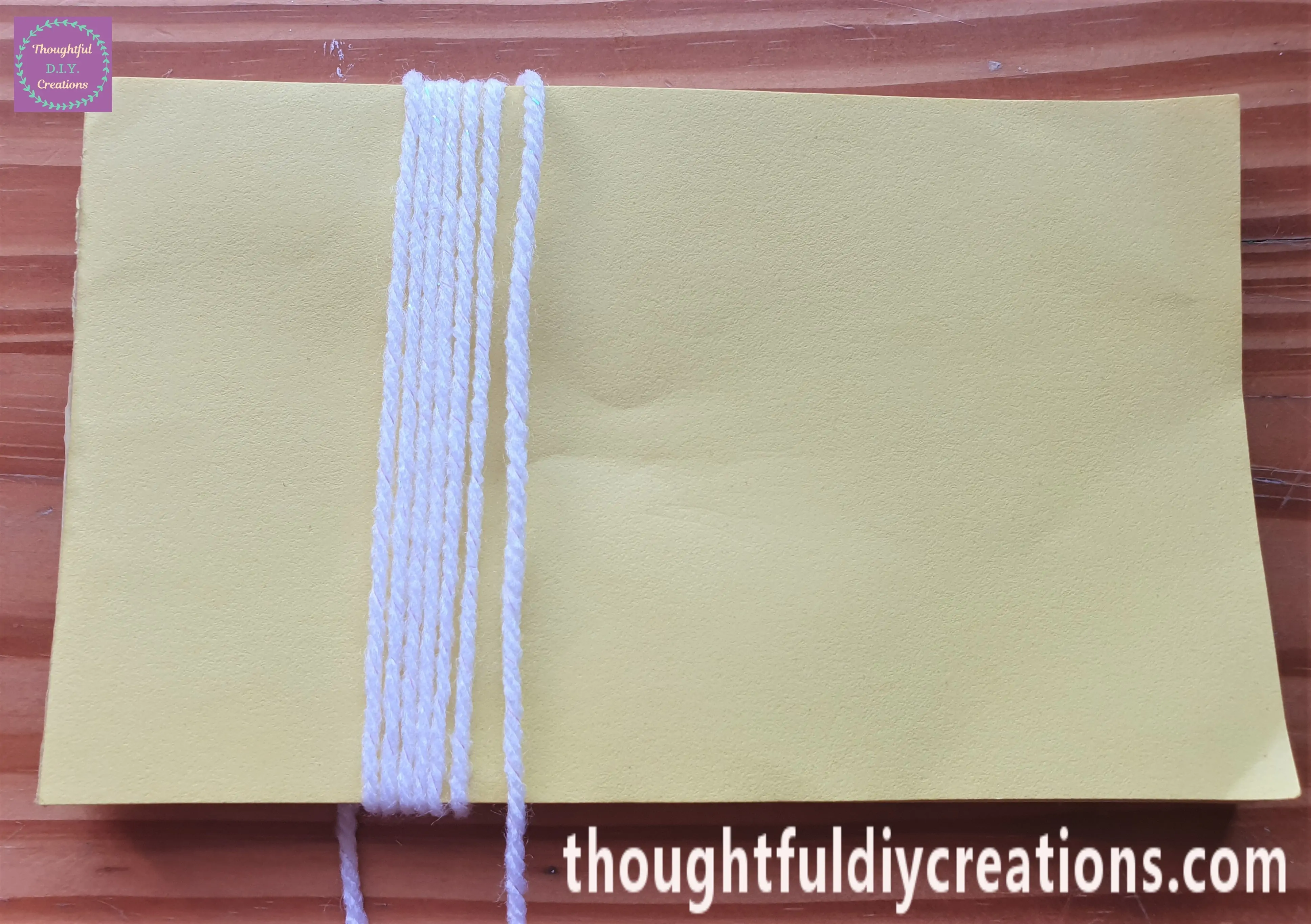 I picked up the String of Wool and Notepad with my left hand and wrapped the wool around the Notepad with my right hand.