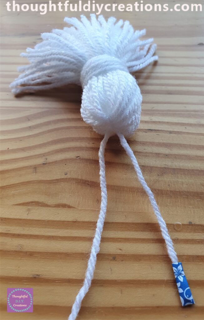I Slid half the String of Wool under the loop of string on top of the tassel.
